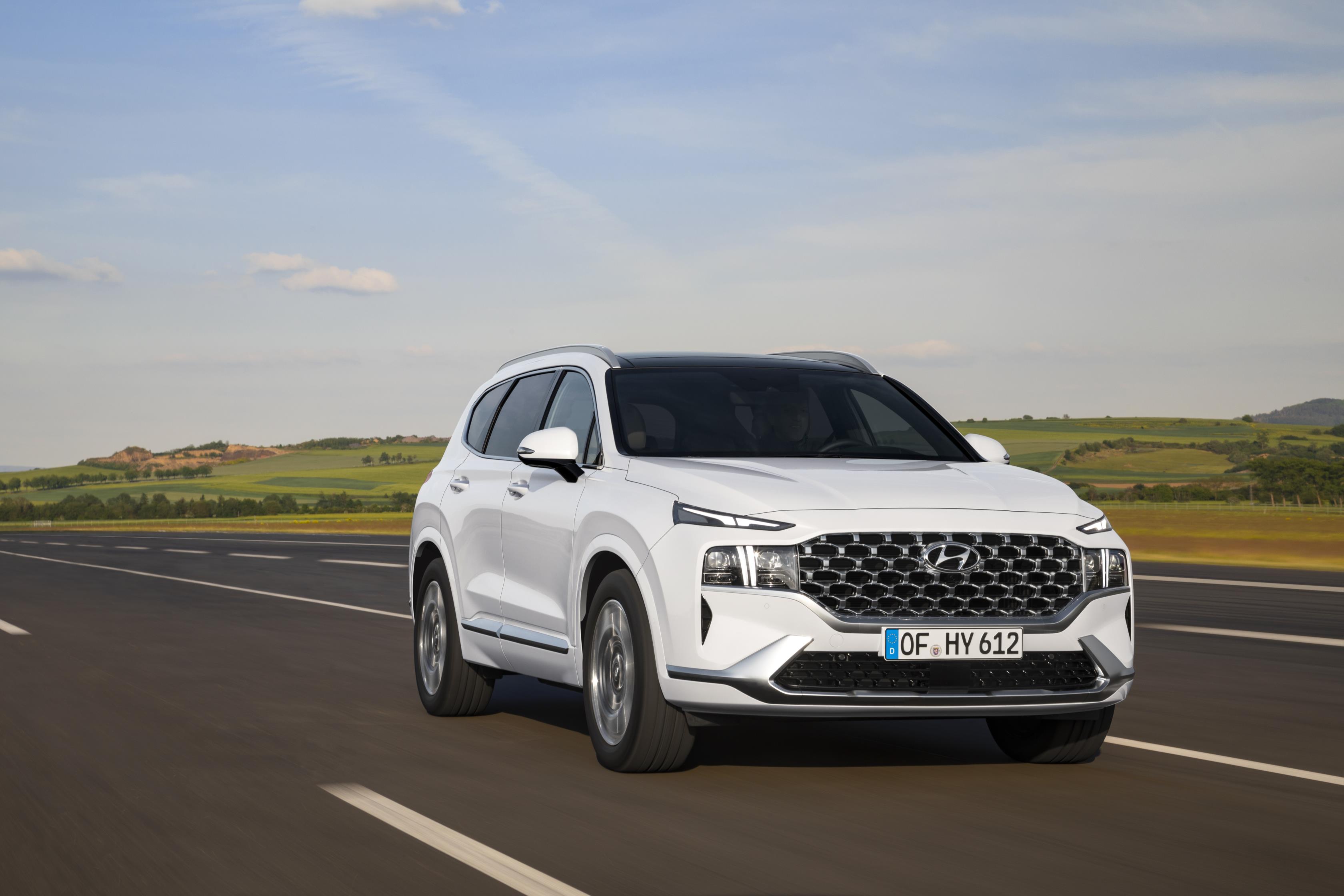 White Hyundai Santa Fe driving front and right side